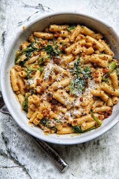 a white bowl filled with pasta and spinach