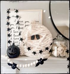 a mantle with halloween decorations on it and a framed photo in the background, along with a pumpkin