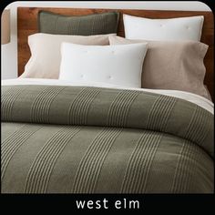 a bed with green and white comforter next to two lamps on either side of the headboard