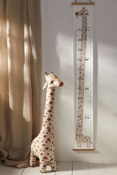 a giraffe standing next to a tall growth chart with a ruler on it