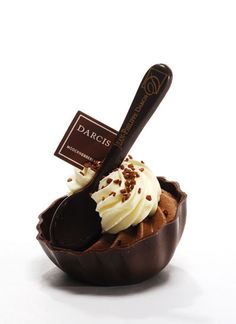 a chocolate cupcake with whipped cream and sprinkles in a bowl on a white background