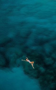 a woman floating in the ocean on top of a surfboard