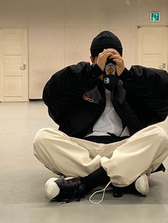 a man sitting on the floor with his hands to his face and holding a camera