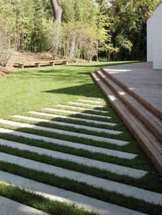 a wooden deck with steps leading up to the grass covered lawn and trees in the background