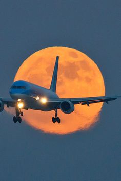 an airplane is flying in front of the moon with it's landing gear down