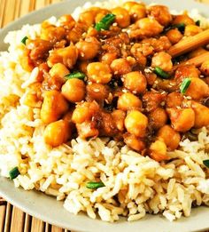 a white plate topped with rice and chickpeas next to chopsticks on a bamboo mat