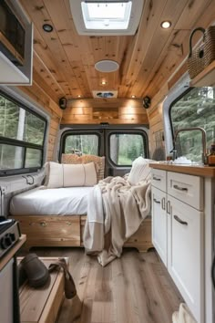 the interior of a camper with wood paneling and white furniture, including a bed