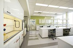 an office with white cabinets and desks on both sides of the room, in front of large windows