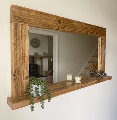 a wooden mirror hanging on the wall next to a potted plant and candle holder