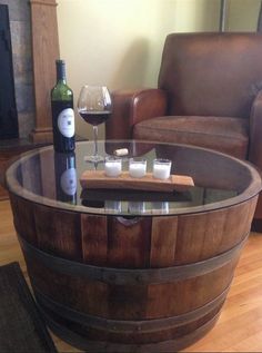 a wooden barrel table with candles and wine glasses on it in front of a couch