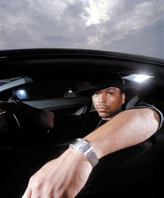 a man sitting in the driver's seat of a car with his hand on the steering wheel