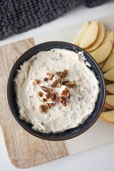 a bowl filled with cream cheese next to sliced apples