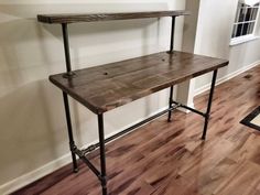 a wooden table sitting on top of a hard wood floor next to a window in a room