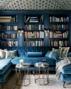 a living room filled with blue couches and lots of bookshelves full of books