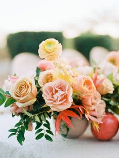 an arrangement of flowers in vases sitting on a white tablecloth with chairs behind them