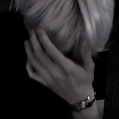 a woman with blond hair holding her hand to her face