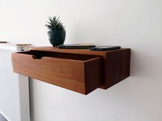 a wooden shelf with a plant and remote control on it's side next to a radiator