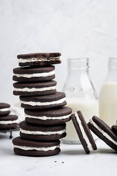 chocolate cookies with white frosting stacked on top of each other next to a glass of milk