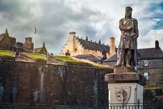 a statue stands in front of a castle