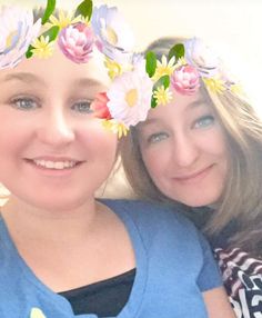 two women with flower crowns on their heads posing for a photo in front of the camera