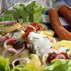 a plate full of food with vegetables and hot dogs