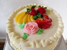 there is a cake with fruit on the top and flowers on the bottom, sitting on a table