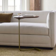 a white couch sitting next to a table on top of a carpeted living room floor