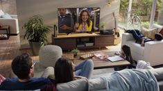 group of people sitting on couches watching tv in living room with large screen television