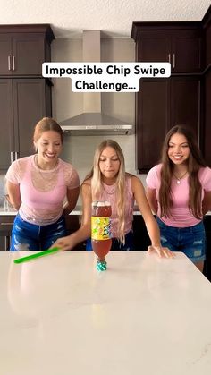 three girls in pink shirts standing at a counter with a jar of ketchup