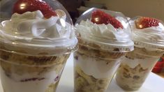 three desserts in plastic cups with strawberries on top