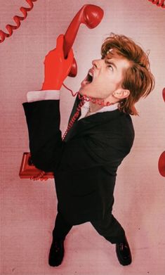 a man in a suit holding a red phone up to his ear