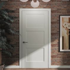 an empty room with a white door and brick wall, potted plant on the floor