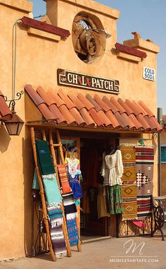 an outside view of a shop with colorful rugs and blankets in front of it