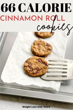 three cookies sitting on top of a baking sheet with a fork in front of them and the words, 66 calorie cinnamon roll cookies