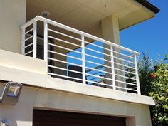 a house with a garage door and railing on the outside, above it is a balcony