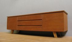 a small wooden cabinet sitting on top of a hard wood floor next to a wall