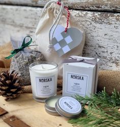 two candles, a bag and some pine cones are sitting on a wooden table next to each other