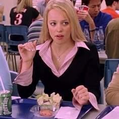 a woman sitting at a table in front of a can of soda and eating food