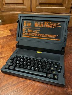 an old laptop computer sitting on top of a wooden table