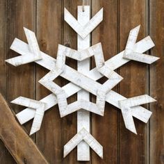 a snowflake made out of white wood sitting on top of a wooden fence