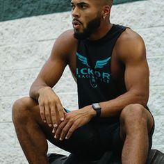 a man sitting on top of a motorcycle wearing a tank top and black shorts with the words ickor racing printed on it