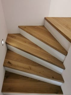 a wooden staircase with white handrails in a house or office building, viewed from the bottom