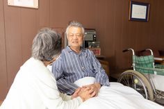 an elderly man in a hospital bed being assisted by a nurse