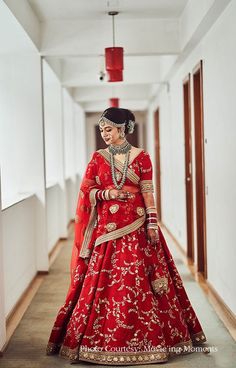 a woman in a red and gold bridal gown is standing on the hallway way