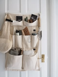 an over the door storage bag hanging on a white wall with various items in it