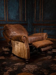 an old leather recliner chair and footstool in a dark room