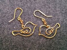 two gold tone earrings with an animal's head on them, sitting on a gray surface