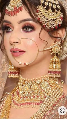 a woman in a bridal outfit with jewelry on her head and veil over her face