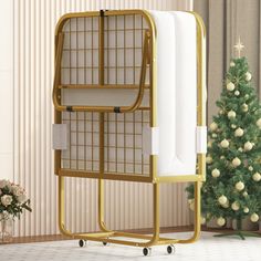 a gold rack with towels on it next to a christmas tree