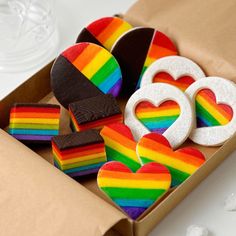 a box filled with rainbow decorated cookies and other treats